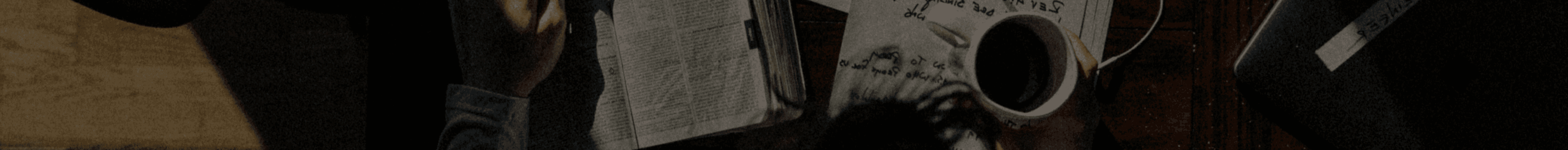 the man is reading a book while holding a cup of coffee